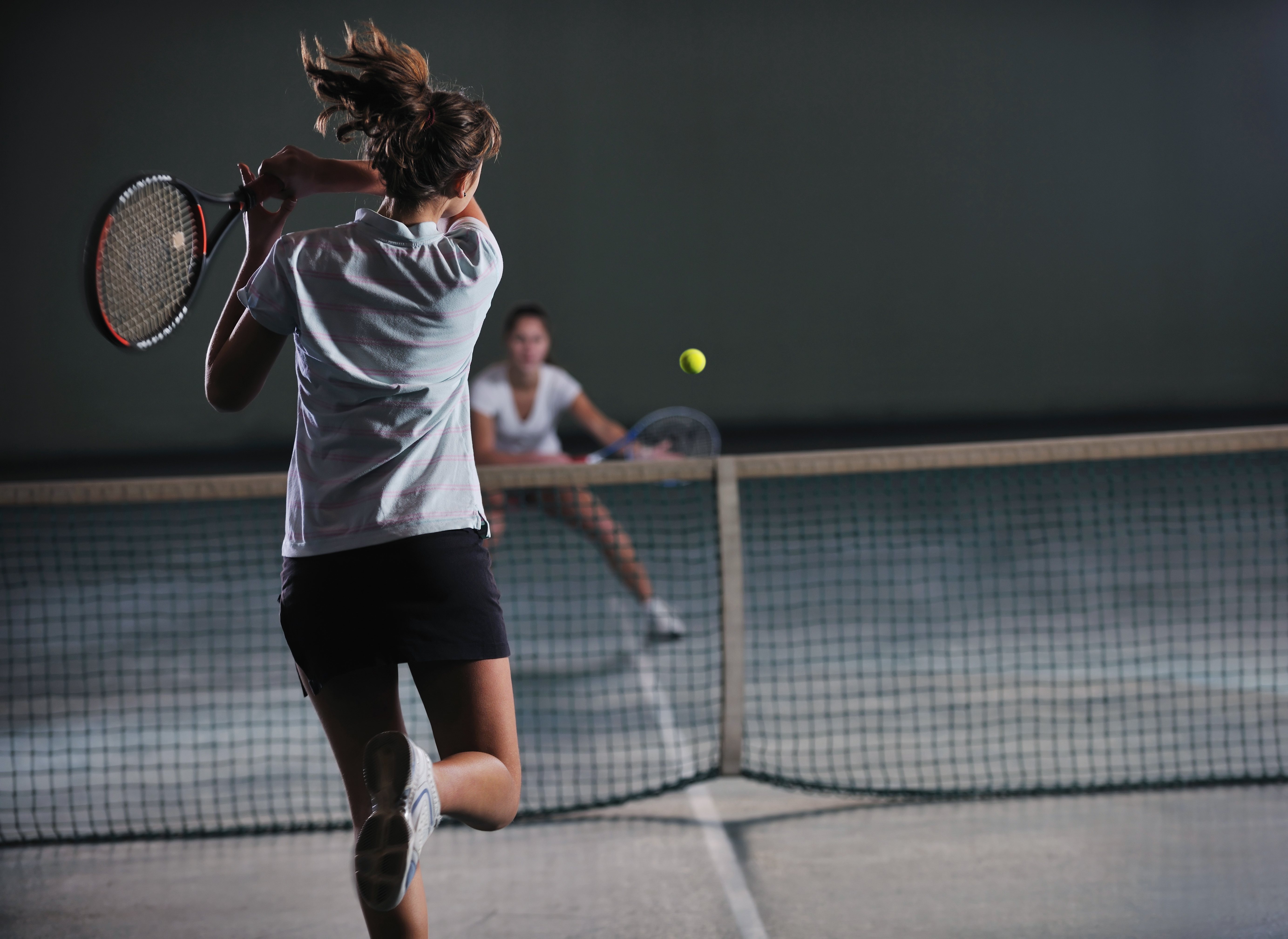 young girls playing tennis game indoori in tennis court